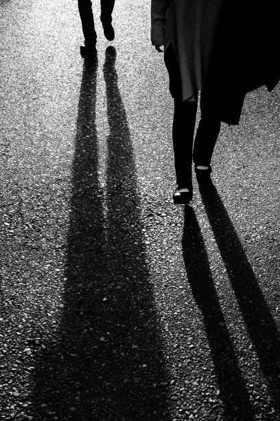 immagine della parte inferiore del corpo di due persone che camminano con la luce sullo sfondo - chasing women men couple foto e immagini stock