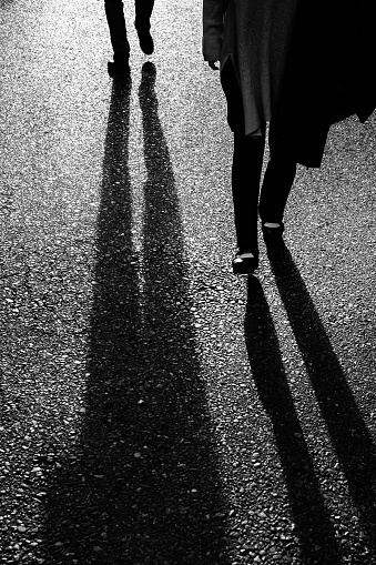 Image of the lower body of two people walking with the light in the background
