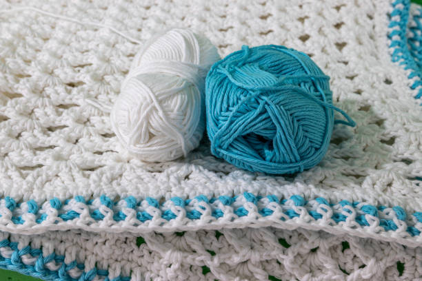 istock Front view of two skeins, one white and one blue on white crochet blanket 1418114618