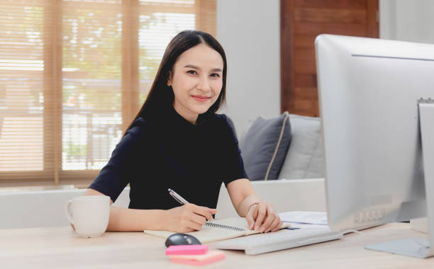 belles femmes asiatiques travaillent et se rencontrent en ligne de la maison via des ordinateurs. interagir avec des collègues avec un visage souriant heureux, une nouvelle activité en ligne normale - looking at camera smiling desk isolated photos et images de collection