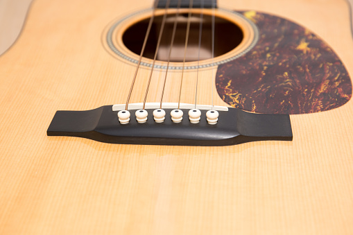 Close-up of the body of an acoustic six-string guitar. Selective focus.