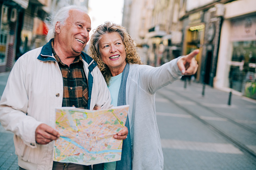 Shot of a elderly couple standing outdoors in the city looking at city landmarks. An adorable mature couple using city map for finding their location.