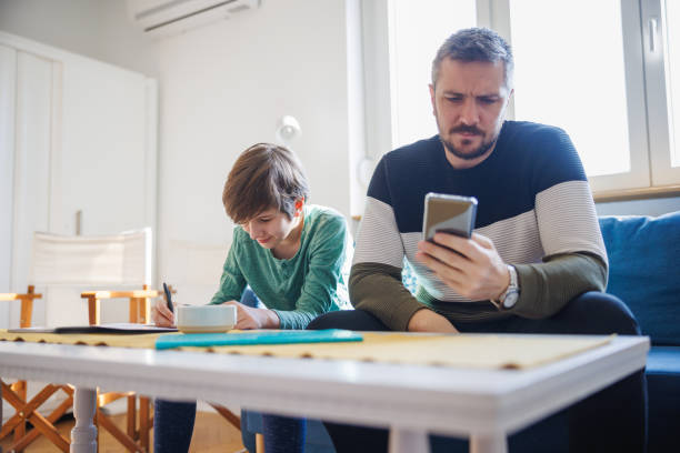 istock Father assisting his home-schooled son at homework, doing research on smart phone 1418133665