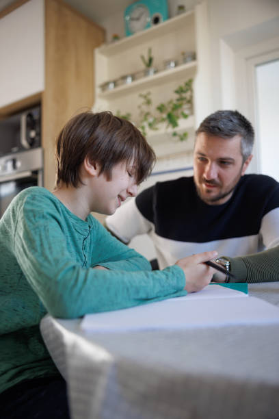 istock Home-schooled boy smiling and discussing task with his tutor 1418133712
