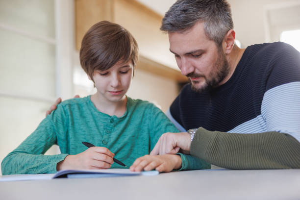 istock Father working on task with his home-schooled son, embracing him for support 1418133810
