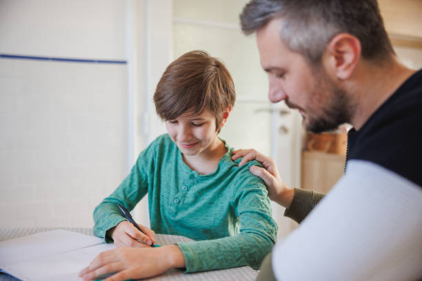 istock Father working on task with his home-schooled son, keeping hand on his shoulder for support 1418133834