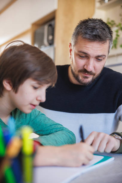 istock Tutor looking at his home-schooled student while he is writing in his notebook 1418133854