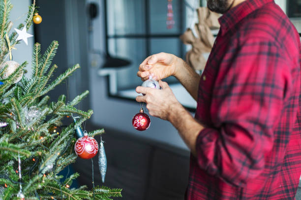 istock Adult man decorating Christmas tree at home 1418135683