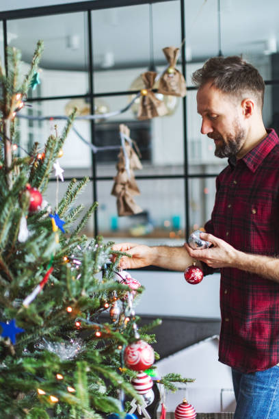 istock Adult man decorating Christmas tree at home 1418135756