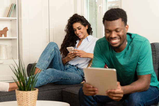 istock Multiracial couple enjoying at home and using smartphone and tablet 1418137315