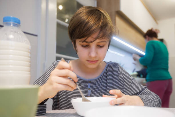istock Boy sitting at the table at home and eating cereal for breakfast 1418140945