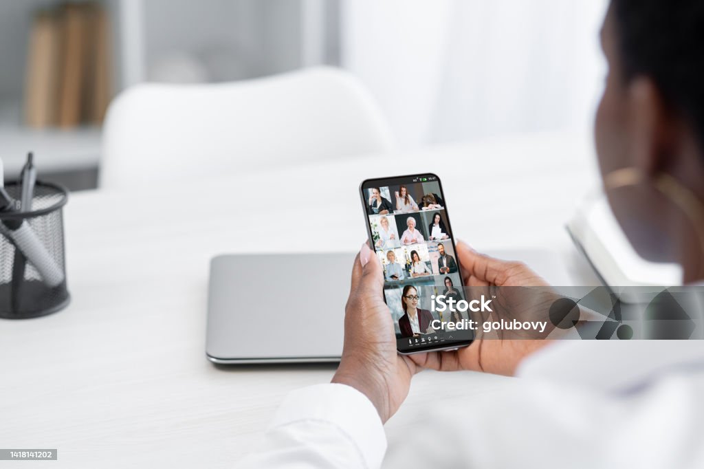 mobile video call online meeting phone online team Mobile video call. Online meeting. Corporate teleconference. Business woman using phone working online with professional team on screen. Brand Name Smart Phone Stock Photo