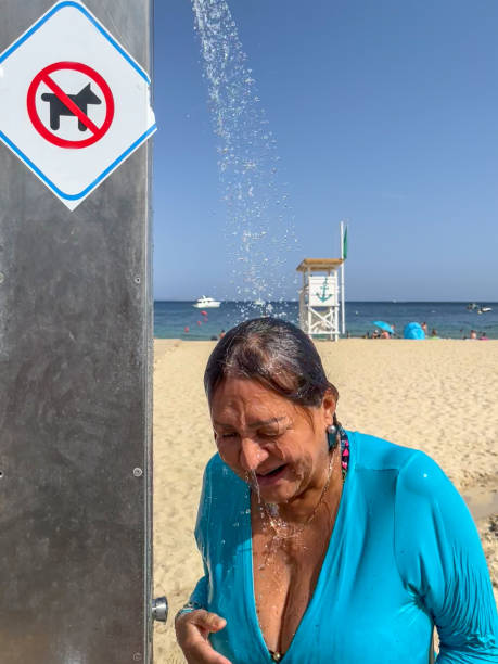 Attractive senior hispanic woman under shower at beach