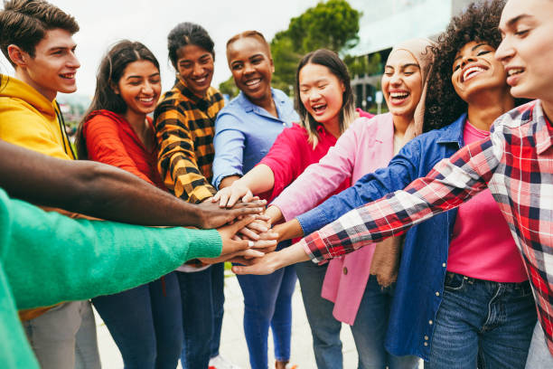 istock Young multiethnic people having fun stacking hands outdoor 1418143463