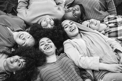 Group of multiracial female friends having fun lying on park grass
