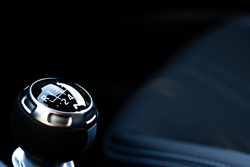 photograph of the manual gearshift lever of a luxury car with dark interior
