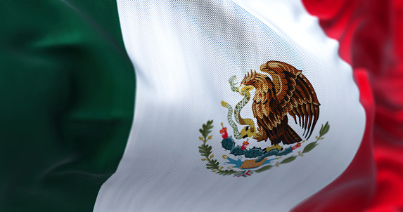 Close-up view of the mexican national flag waving in the wind. Mexico is a country in the southern portion of North America. Fabric textured background. Selective focus