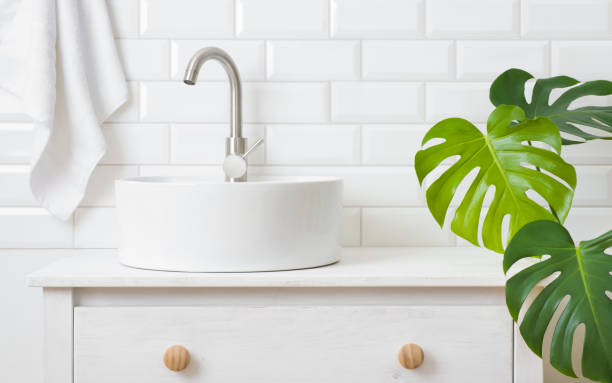 istock Sink on countertop in bathroom with plant and tile wall 1418146024