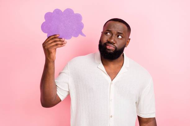 istock Photo of funny unsure guy dressed white shirt smiling looking mind cloud empty space isolated pink color background 1418146062