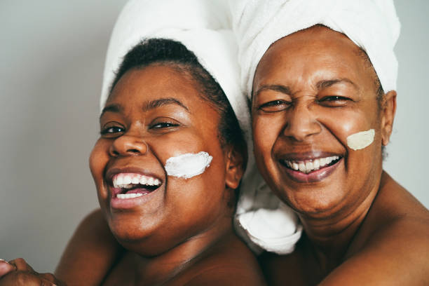 mãe e filha africanas fazendo tratamento de beleza em casa usando máscara de pele - foco no rosto de menina - aging process women human face daughter - fotografias e filmes do acervo
