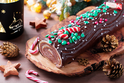 Traditional chocolate trunk cake or log cake on table with Christmas decorations, top view