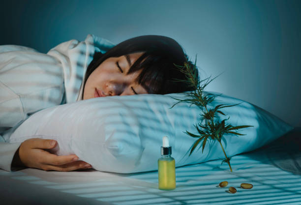 asian girl sleeping in evening bedroom with cbd oil, capsules and a cannabis branch. melatonin production, concept of combat sleep disorders - narcotic medicine pill insomnia imagens e fotografias de stock