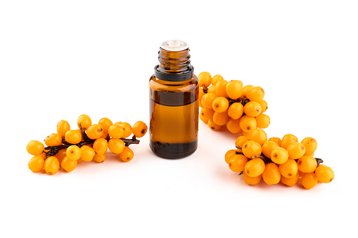 Glass bottle with sea-buckthorn oil, berries isolated on white background. Self-care, cosmetics, beauty practices, self-care concept.