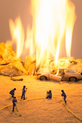 Miniature firefighters and car on fire scene