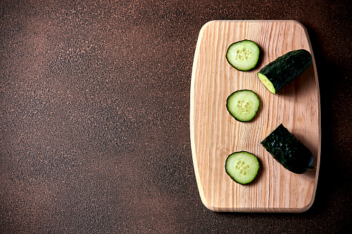 Sliced cucumber on cutting board on a rustic wooden table