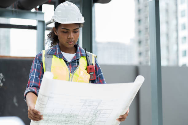 istock Woman engineer working with construction building blueprint at sewer pipes area at construction site on rooftop of building 1418155768