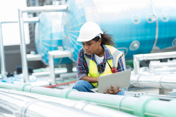 istock Female engineer work using laptop computer for checks or maintenance in sewer pipes area at construction site. African American woman engineer working in sewer pipes area at rooftop of building 1418155770