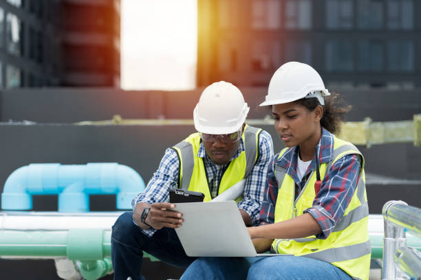 grupo de ingenieros afroamericanos que trabajan en el área de tuberías de alcantarillado en el sitio de construcción. ingeniero masculino y mujer ingeniero discutiendo para el mantenimiento de tuberías de alcantarillado, tanque de agua en la azotea del - rutina técnica fotografías e imágenes de stock