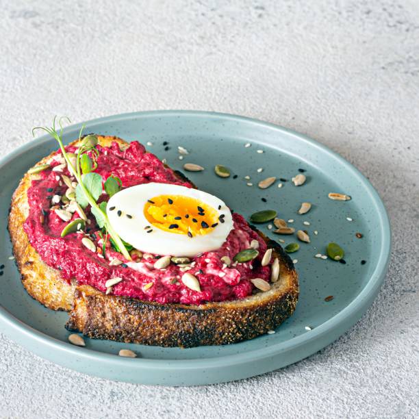 istock Whole grain toast with beetroot hummus, seeds, egg and microgreens (sprouted pea sprouts) on a light gray background. The concept of healthy eating.. 1418155852