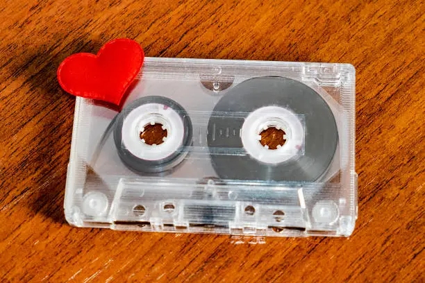Audio Tape Cassette with a Red Heart on the Wooden Table closeup