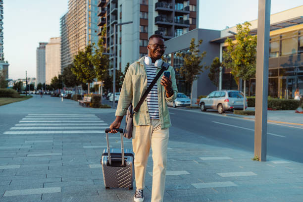 istock Young man walking through the city streets with suitcase 1418159565