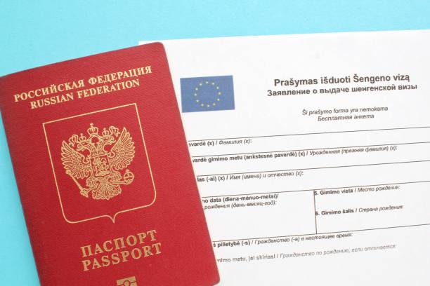 istock Schengen visa application form in Russian and Lithuanian language and passport on blue background 1418161100
