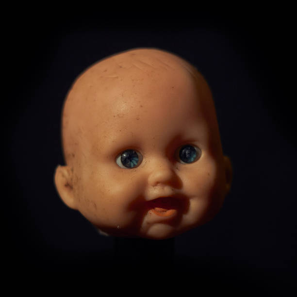 istock Damaged Dirty Doll head on black background 1418163141