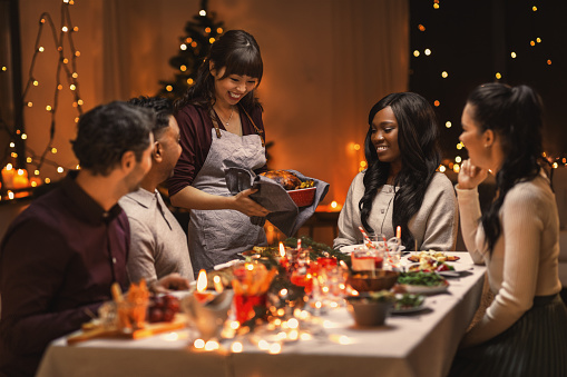holidays and celebration concept - multiethnic group of happy friends having christmas dinner at home