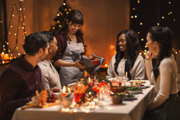 happy friends having christmas dinner at home holidays and celebration concept - multiethnic group of happy friends having christmas dinner at home political party stock pictures, royalty-free photos & images