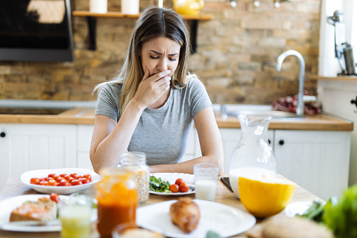 Mujer que se siente enferma durante la hora del desayuno en el comedor photo