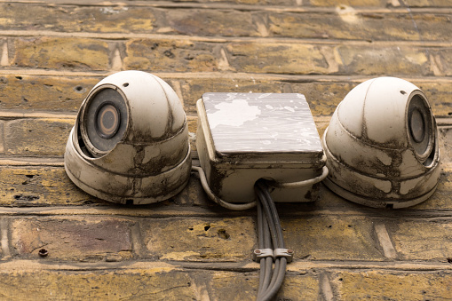 Close up of two mounted on facade dirty white surveillance ccd cameras looking as eyes concept monitoring video security surveillance
