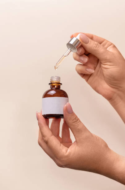 istock Hands holding pipette and opened dropper bottle over light beige, cosmetic mockup 1418173805