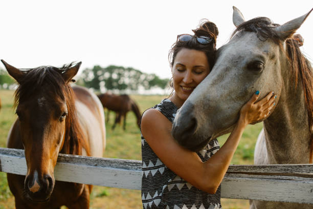 Young woman spending time with her horses, on a bright and beautiful summertime day.