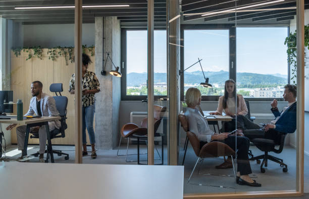 Multiracial colleagues talk in meetings while preparing tasks and work plans. they stand in front of a glass wall with leaflets.