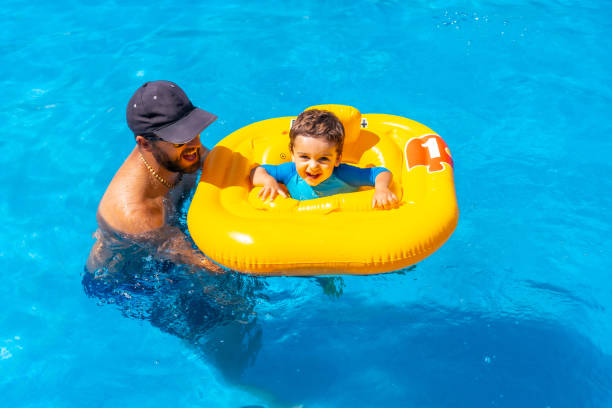 istock Father playing with his son with a yellow float in the pool in summer 1418179543