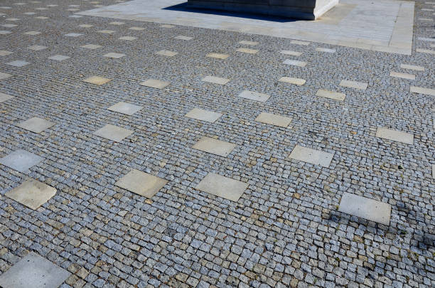 granite cobblestone tiles in a large area and inside cut irregularly placed cut stone slabs, stone tiles squares in a finer paving of granite mosaic cubes in an irregular dispersion contrasting size