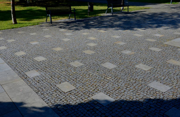 istock granite cobblestone tiles in a large area and inside cut irregularly placed cut stone slabs, stone tiles squares in a finer paving of granite mosaic cubes in an irregular dispersion contrasting size 1418182492