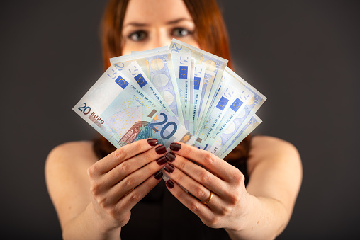 Red head woman holding Euro bills fanned out