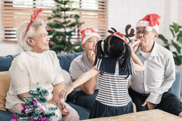 senior and grandchild group of family having fun celebrate christmas and new years party at home - 65 69 years stok fotoğraflar ve resimler