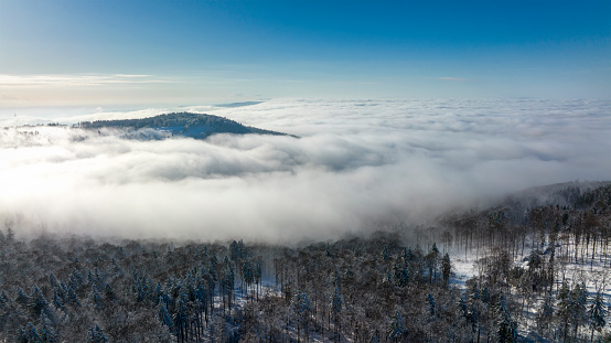 Aerial view of Taunus mountains on a sunny and cold winter day. Fog and clouds above the forest